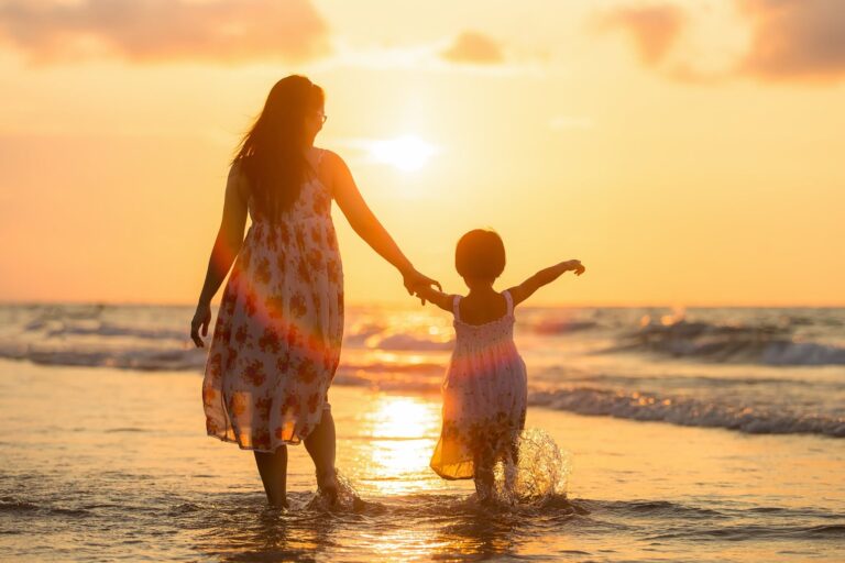 A mother and young daughter holding hands, walking